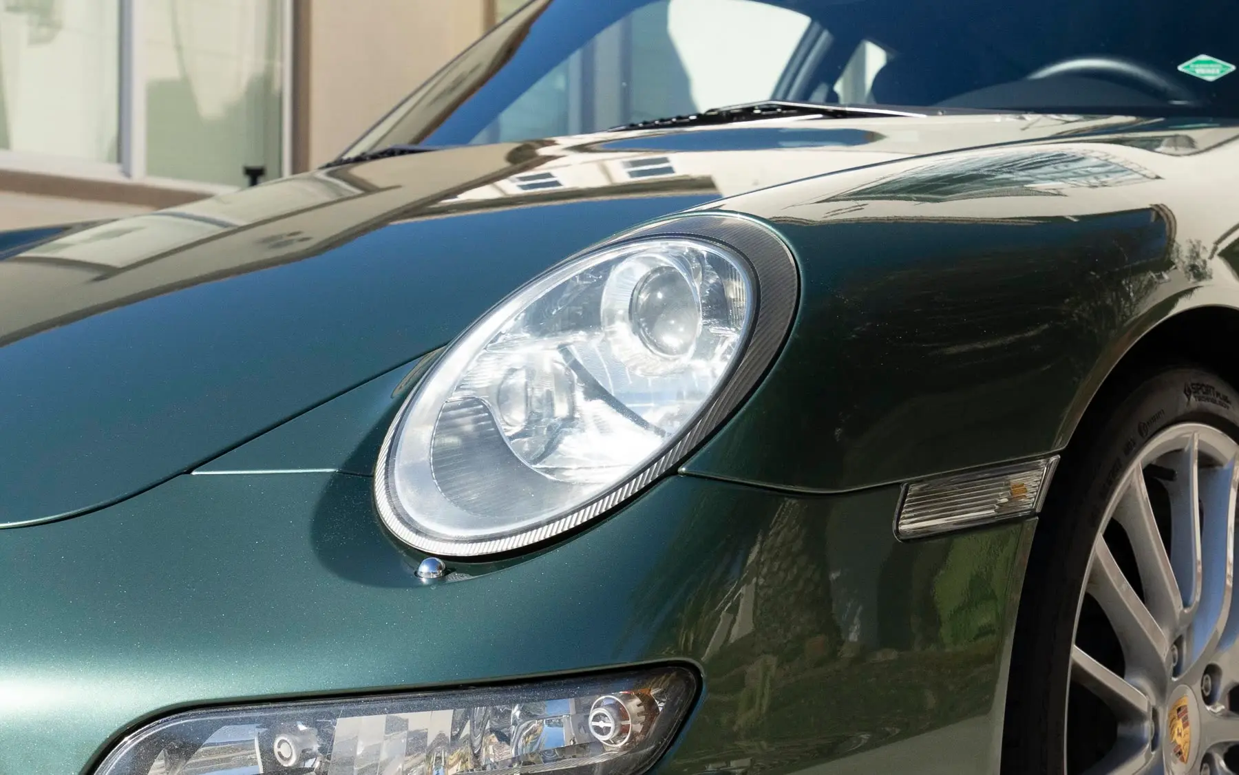 The same Porsche 911 headlight, polished clear after correction