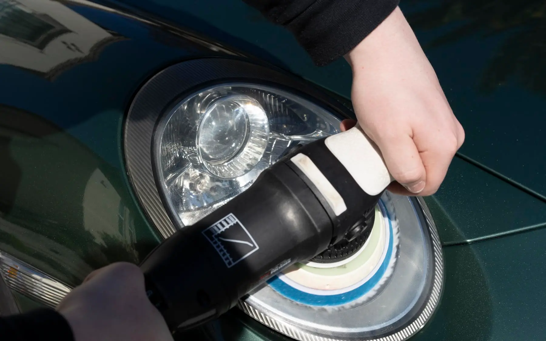 Hazy, oxidized headlight on a green Porsche 911 before correction